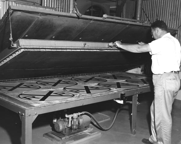 A State Road Department employee works on a batch of standardized railroad crossing signs at the Department's sign shop in Lake City (circa 1950s).