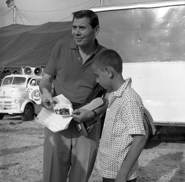Gene Rayburn showing instant camera photograph to a boy at the Cristiani Brothers Circus during rehearsal for NBC-TV in Sarasota, Florida, 1959