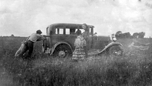 Mikasuki Indians help Deaconess Bedell free her car from the mud in South Florida (circa 1930s-1940s).