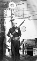 Chief Petty Officer Charles H. Brems holding a rifle aboard the USS Massachusetts.
