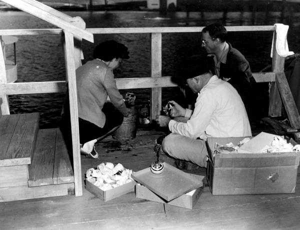 June Manson hands diver Newt Perry water-filled ornaments to decorate underwater Christmas tree..
