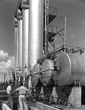 Employees stand beside huge drums at Gulf Naval Stores Company - Nocatee, Florida.