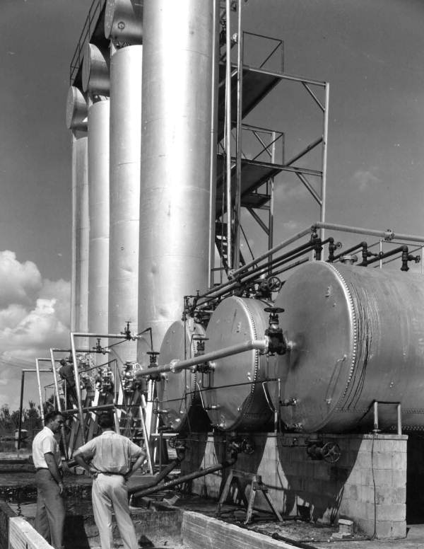 Employees stand beside huge drums at Gulf Naval Stores Company - Nocatee, Florida.