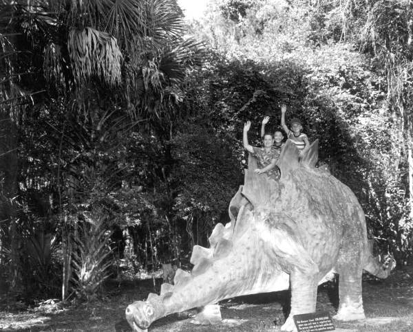 Children perched atop a concrete Stegosaurus dinosaur at Bongoland (1959).