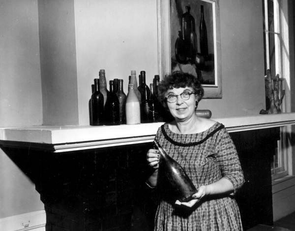 Woman posing with a bottle of wine in deBary Hall, the Volusia County winter home of New York City wine importer Frederick DeBary, who also had fruit groves near Lake Monroe.