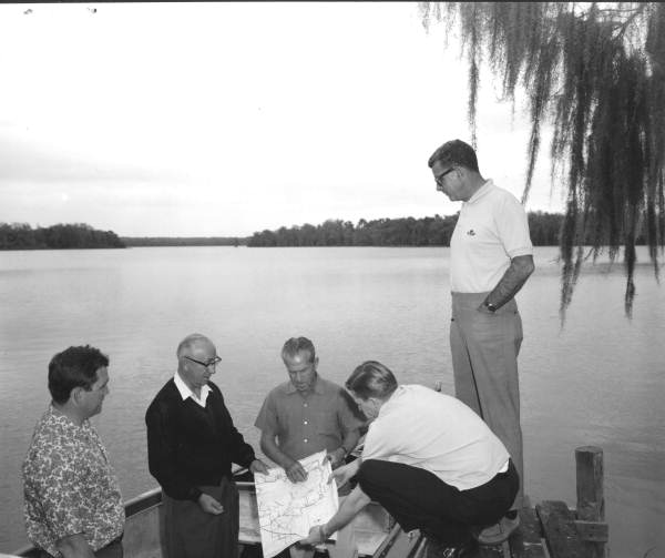 Disney representatives looking over a map while inspecting the Disney property fronting Lake Buena Vista (circa 1965).