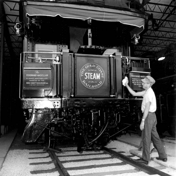 An employee cleaning a steam locomotive displayed at the Gold Coast Railroad Museum - Fort Lauderdale, Florida.