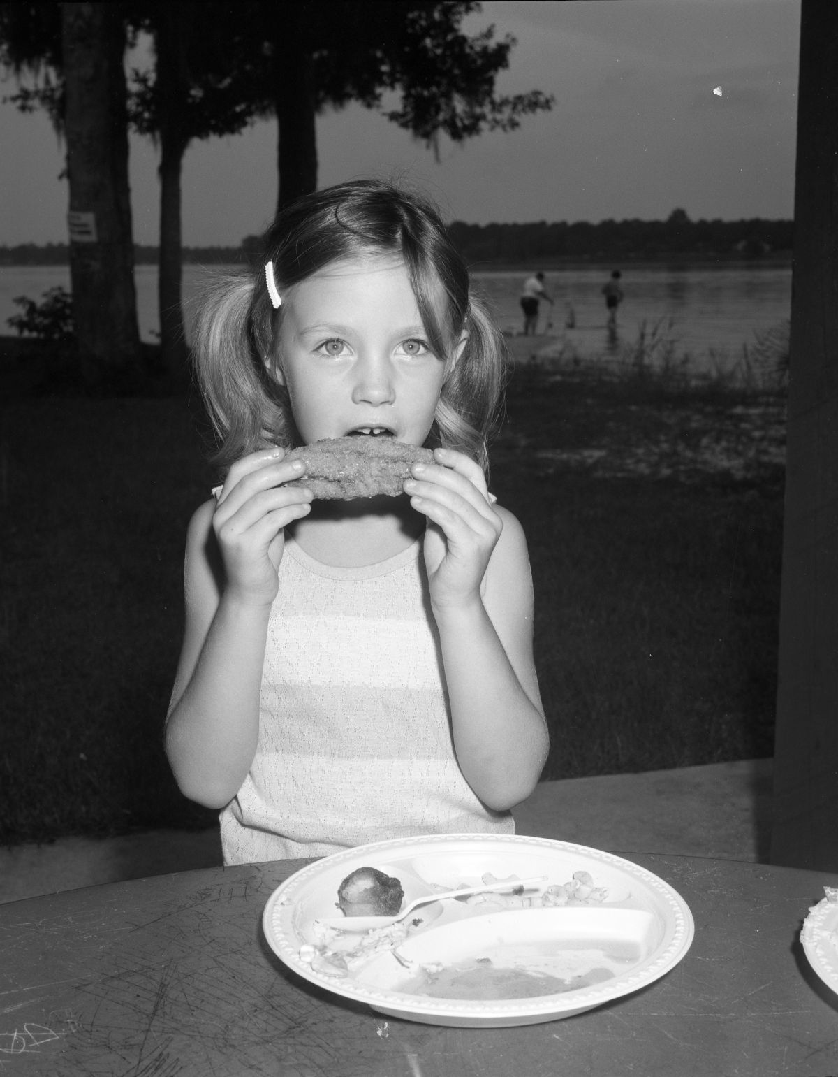 Young girl eating fried mullet at the Bayou Mullet Festival in Niceville (1978).