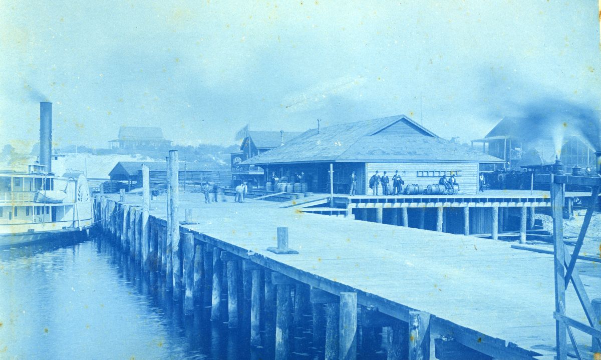 Barrels being moved between steamboat and building at dock in Carrabelle, Florida, February 1899