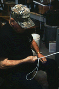 Close-up view showing whipmaker Ernest "Shelby" Braddock braiding a cow whip in the shop at his home in De Land, Florida.