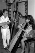 Jesus Rodriguez playing cuatro while apprentice Cecilia Santos plays Venezuelan harp- Miami, Florida