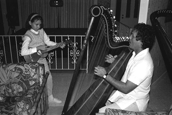 Jesus Rodriguez playing Venezuelan harp while apprentice Ana Maria de Armas plays the cuatro- Miami, Florida.