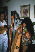 Jesus Rodriguez playing cuatro while apprentice Cecilia Santos plays Venezuelan harp- Miami, Florida.