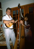 Jesus Rodriguez playing cuatro while apprentice Cecilia Santos plays Venezuelan harp- Miami, Florida