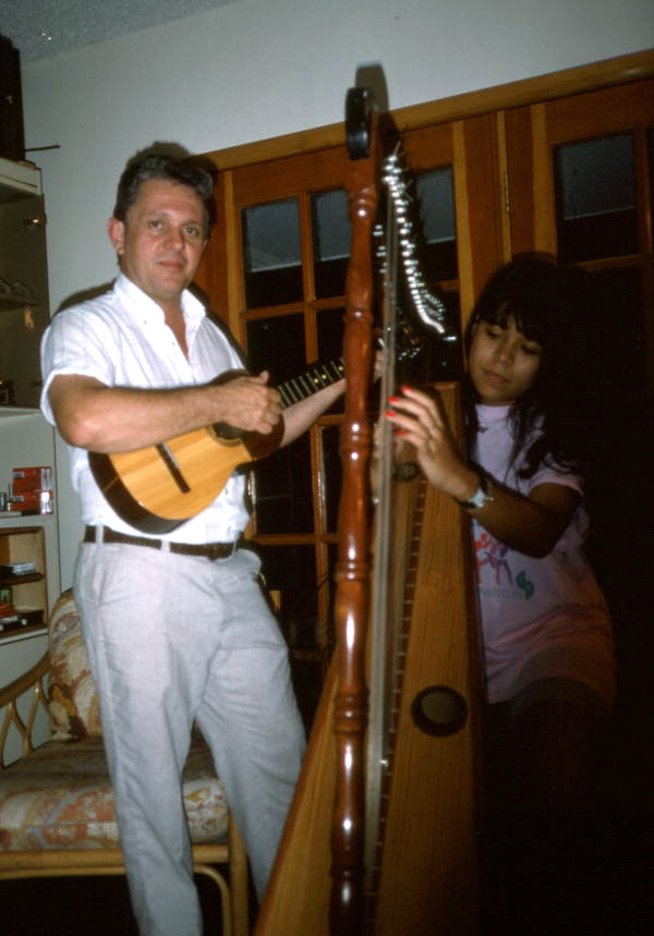 Jesus Rodriguez playing cuatro while apprentice Cecilia Santos plays Venezuelan harp- Miami, Florida