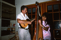 Jesus Rodriguez playing cuatro while apprentice Cecilia Santos plays Venezuelan harp- Miami, Florida.