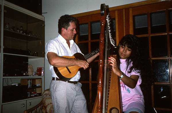 Jesus Rodriguez playing cuatro while apprentice Cecilia Santos plays Venezuelan harp- Miami, Florida.