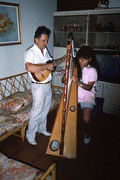 Jesus Rodriguez playing cuatro while apprentice Cecilia Santos plays Venezuelan harp- Miami, Florida.