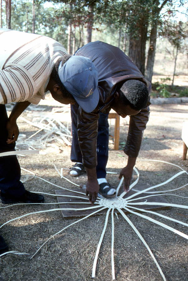 Apprentice Michael Steen (L) watches teacher Alphonso Jennings as he lays out the pattern of a white oak basket - Lamont, Florida