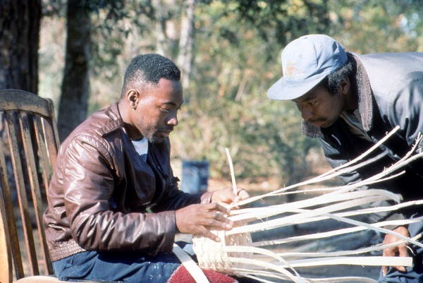 Apprentice Michael Steen (R) watches teacher Alphonso Jennings weave a white oak basket - Lamont, Florida
