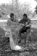 Apprentice Reginald Reis works on a cast net while master netmaker Max Dooley looks on - Lakeland, Florida.