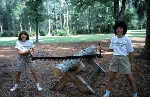 Debbie Fant, left, and Riki Saltzman holding cross-cut saw at Fourth of July celebration - White Springs, Florida