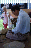 Tuyen Pham tying together pieces of whittled wood to make a basket- Pensacola, Florida.