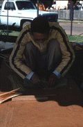 Tuyen Pham tying together pieces of whittled wood to make a rice basket - Pensacola, Florida.