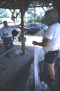 Costa Buzier hanging a trawl net and sewing webbing while Marcus Hepburn looks on - Apalachicola, Florida.