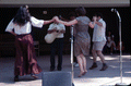 Nikitas Tsimouris playing a tsambouna while Greek dancers perform around him - White Springs, Florida