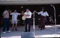 Nikitas Tsimouris playing a tsambouna while Greek dancers perform around him - White Springs, Florida