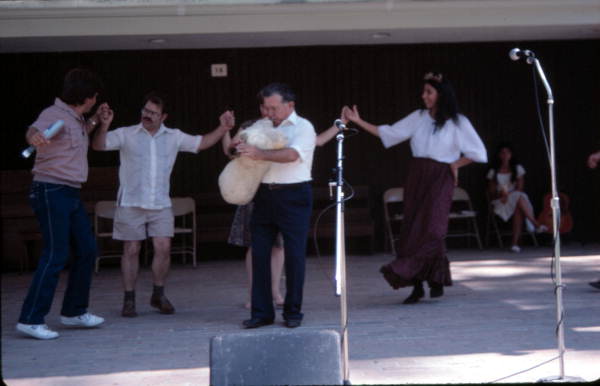 Nikitas Tsimouris playing a tsambouna while Greek dancers perform around him - White Springs, Florida