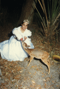 Young woman feeding fawn during Quinceanera ceremony.