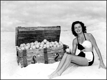 Margie Fletcher in a beach scene, posing with an orange-filled treasure chest: Winter Haven, Florida (1949)