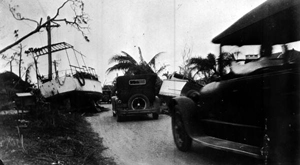 Cars driving by boats washed ashore from the 1926 hurricane: Miami, Florida