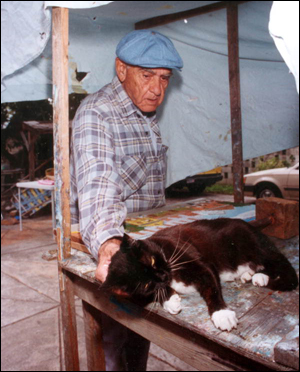 Mario Sanchez taking a break from his art work to pet his cat: Key West, Florida (1992)