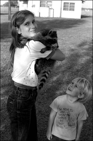 April and Michael McQuaig with their pet raccoon at El Maximo Ranch: Frostproof, Florida (1984)