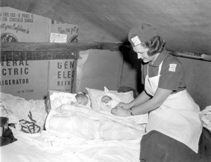 Florida State University public health nurse checking twins born to migrant worker family (195-)