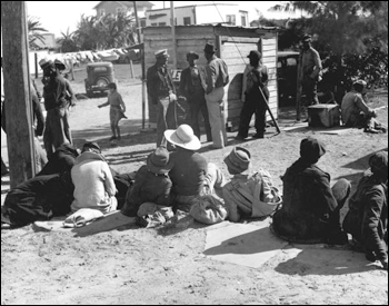 Migrant workers waiting for a truck to take them to the bean fields: Lake Harbor, Florida (1939)