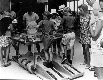 Boys look at an exhibit while standing on the tread of a crawler-transporter: Cape Canaveral Florida(19--)