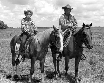 Seminole Indian cowboy Charley Micco and grandson Fred Smith on horseback in a cattle ranch: Brighton Reservation, Florida. (1950)
