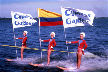 View showing water skiers holding flags during performance at the Cypress Gardens theme park in Winter Haven, Florida (19--)