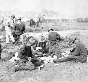 Rough Riders filling belts with cartridges (1898)