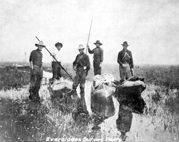 A 1913 Everglades survey party. Though smaller in number, their equipment is similar to what the Times Democrat expedition would have been outfitted with. You can see a somewhat larger boat in the background, fitted with a mast for a small sail.