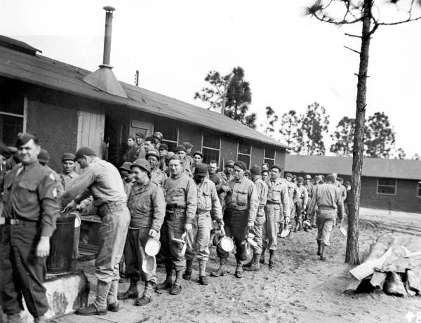 Soldiers wait in a chow line with mess kits in hand at Camp Gordon Johnston (circa 1943).