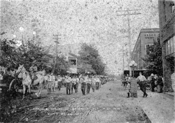 A Memorial Day parade heading down Main Street in Wauchula. According to a note accompanying the original image, this was the last parade in Wauchula to be held on dirt roads in the town (1915).