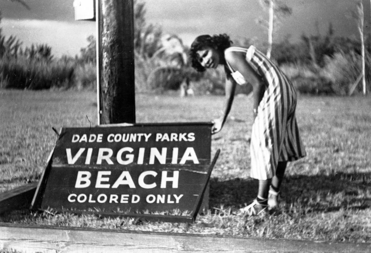 A woman stands by the sign for Virginia Beach in Miami, which was designated for African-American use only. The sign had been blown down in a recent storm (1950).