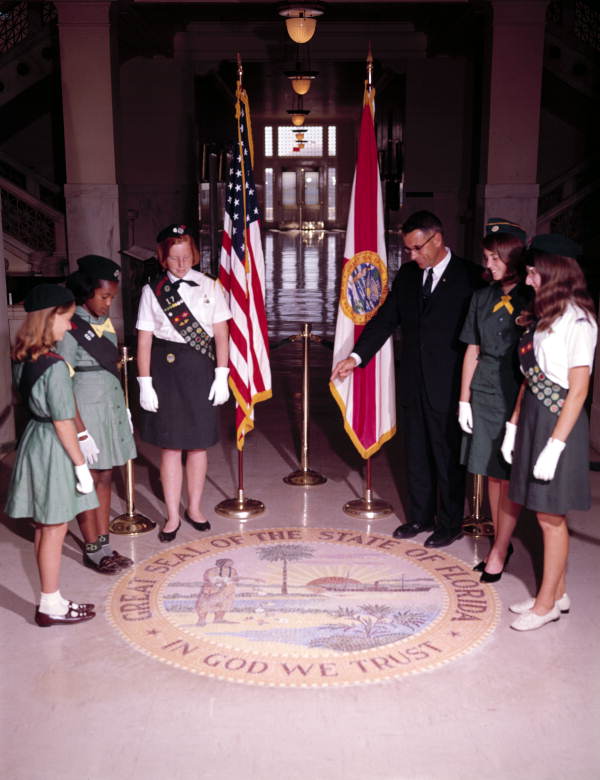 Secretary of State Tom Adams pointing out features of the State Seal on the capitol floor to some girl scouts.