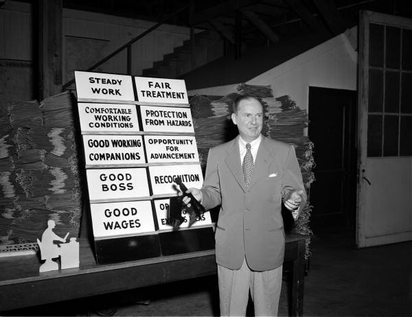 Unidentified employee with poster describing work conditions and environment at the Bemis Bro Bag Company - Jacksonville, Florida.