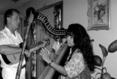 Jesus Rodriguez playing cuatro while apprentice Cecilia Santos plays Venezuelan harp- Miami, Florida